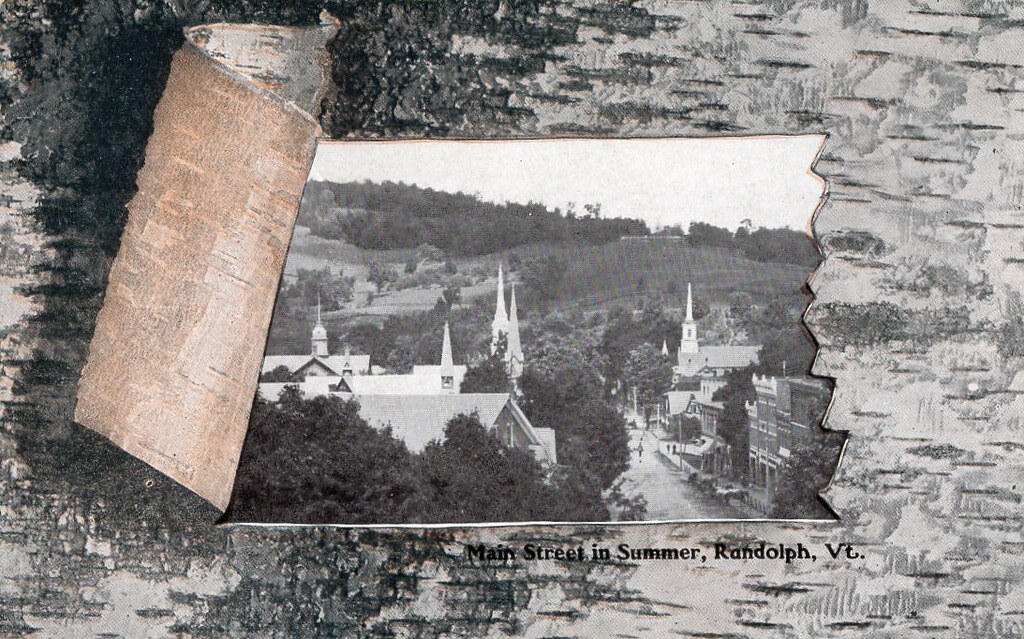 postcard view of randolpg showing mostly curch spires. It's framed by a birch border, peeled back to reveal the image of the town