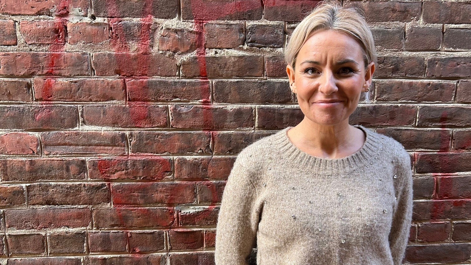 woman in front of red brick wall