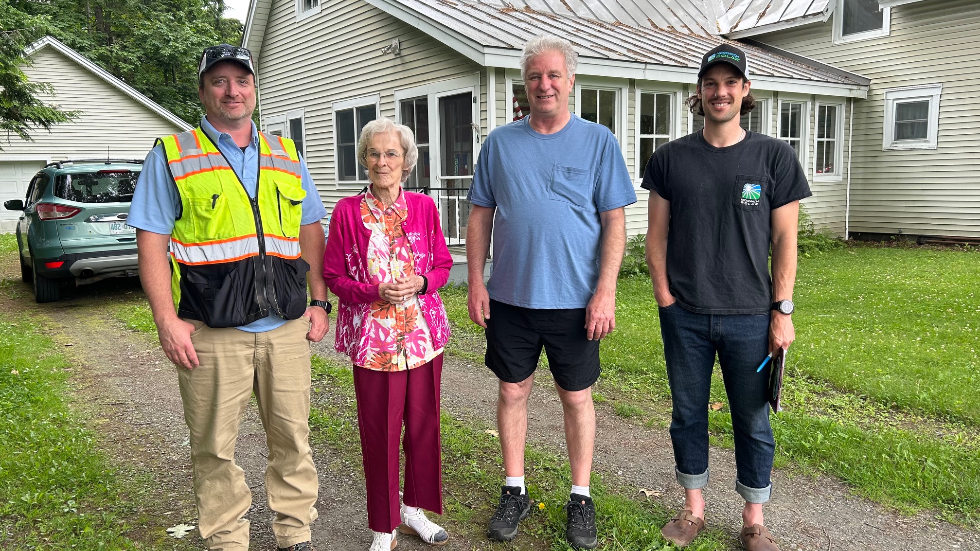 four people standing outside in front of a home