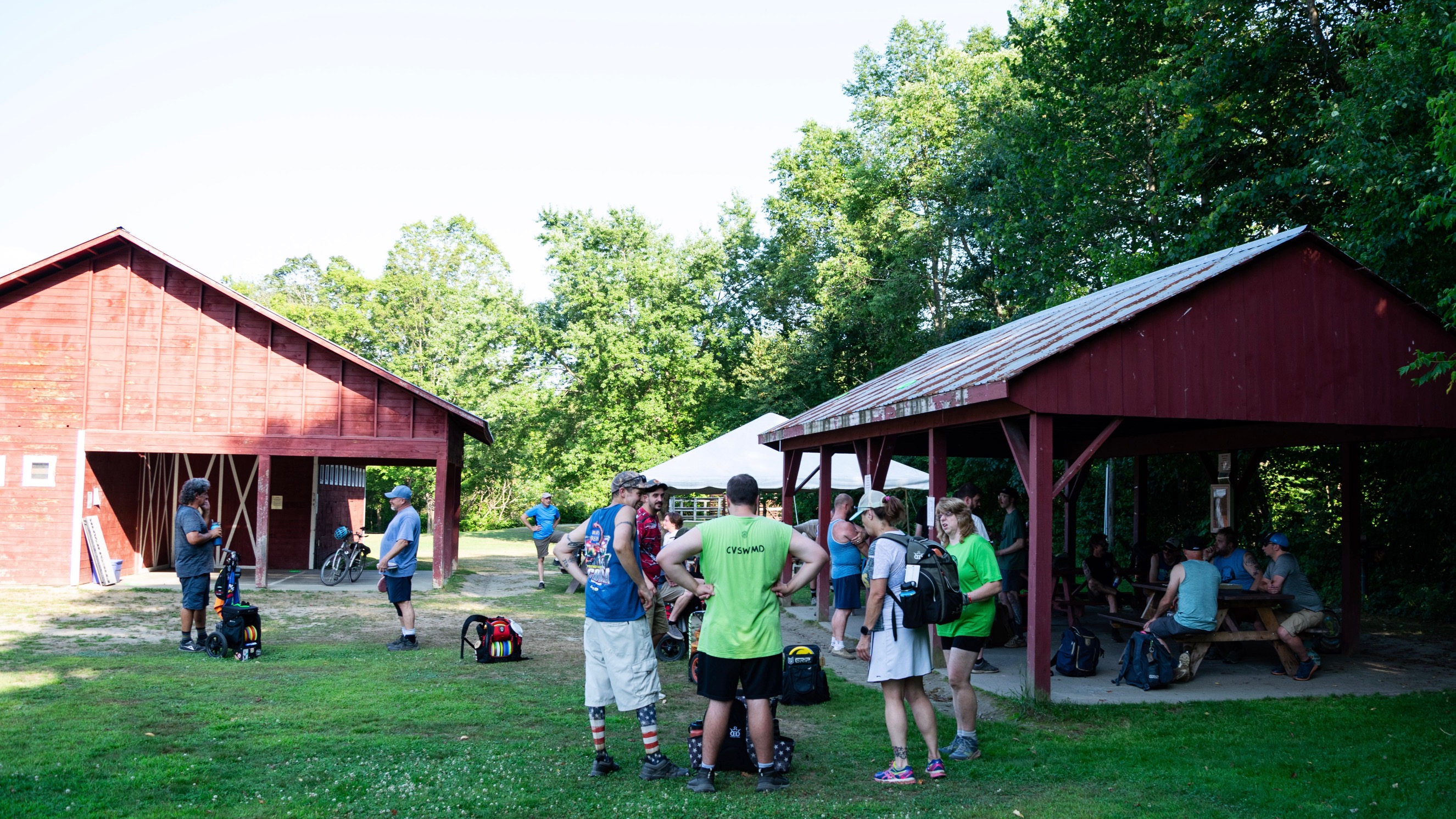 several paople outside beside red barns