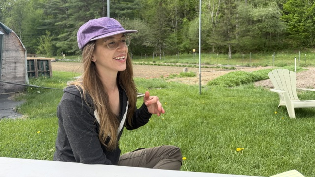 Sarah sitting on a bench laughing w gardens in background