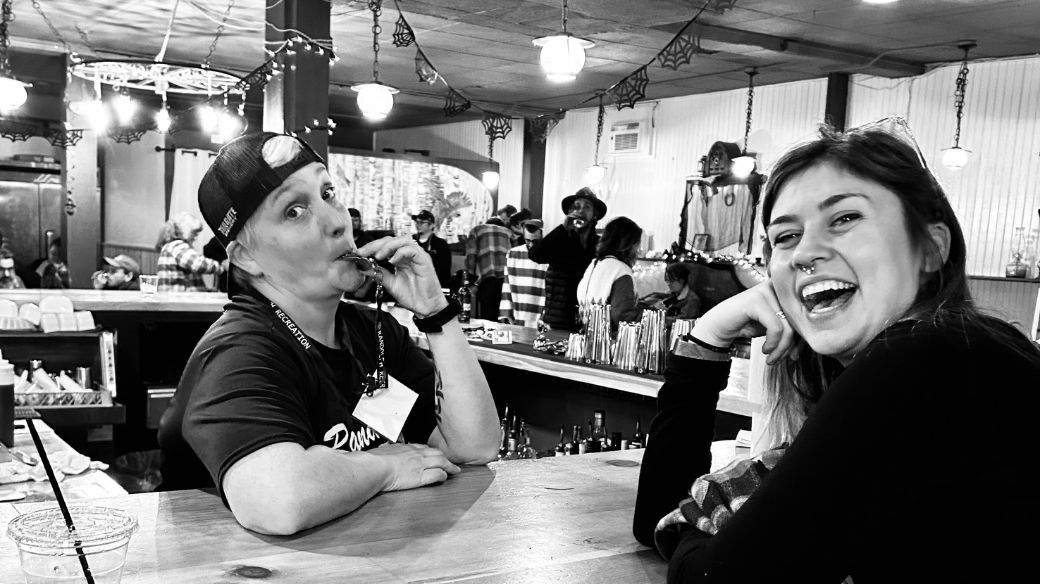 Hannah at the bar laughing w a customer