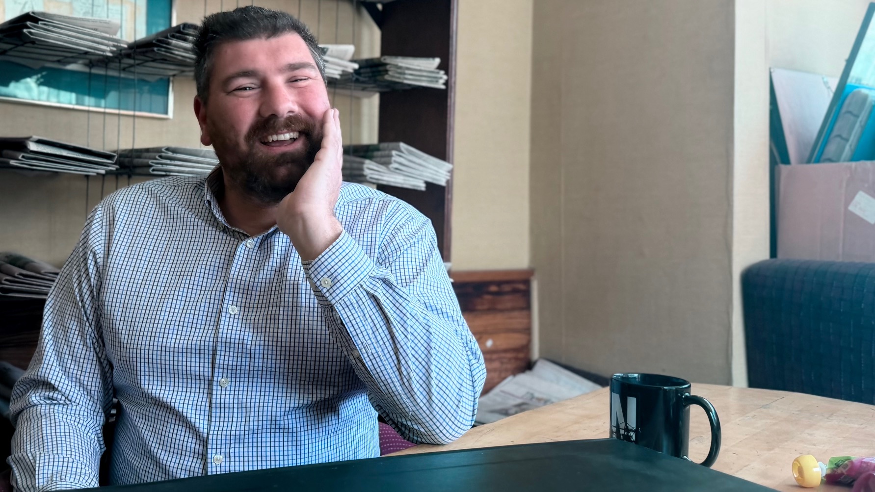 Tim Calabro sitting at a table smiling while his hand is on his face